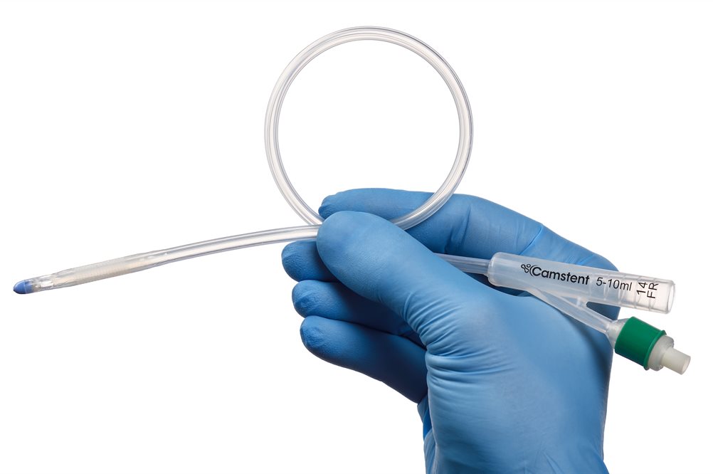 A gloved hand holding a catheter