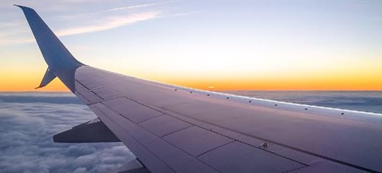 Looking out over a plane wing in the air at sunset