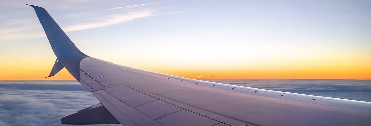 View over a plane’s wing mid-flight at sunset