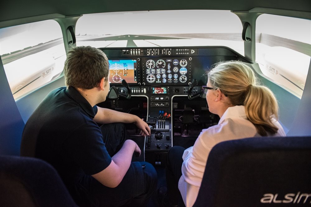 A man and woman sat inside an aeroplane simulator