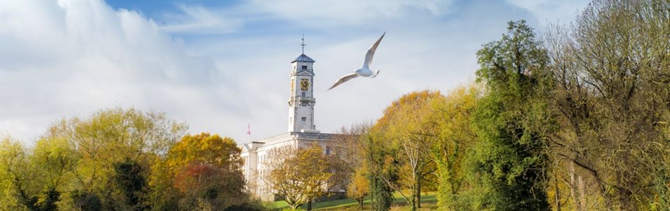 A bird flies over the lake at the University of Nottingham, the Trent Building is visible in the background.