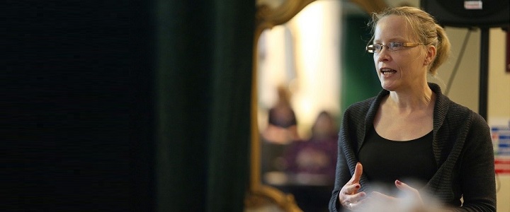 Photo of woman with blonde hair gesturing to left of image