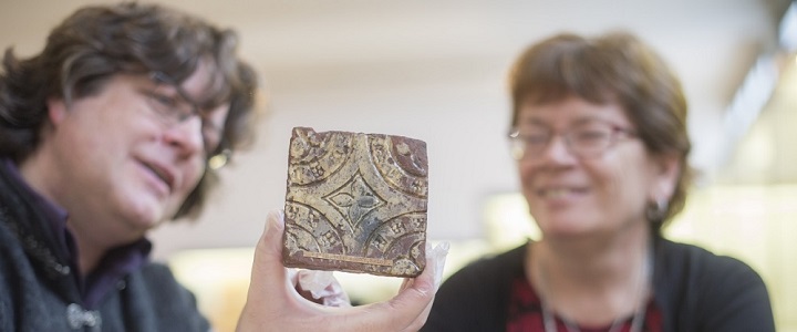Photograph of a white man and woman looking at a carved piece of stone