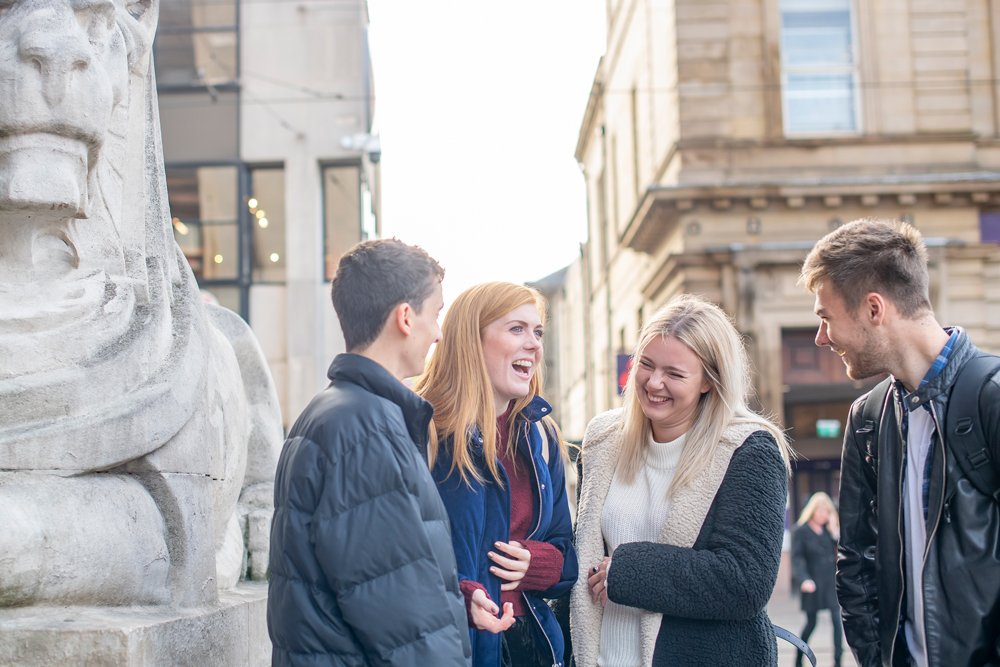 Four students laughing outside in the Old Market Square