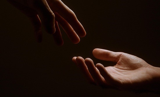 A hand reaching for another hand in support