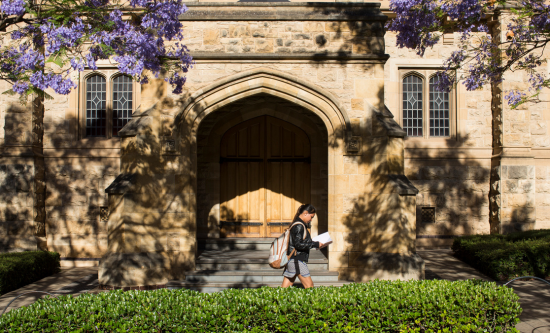 Photo of student walking down outdoor hallway.