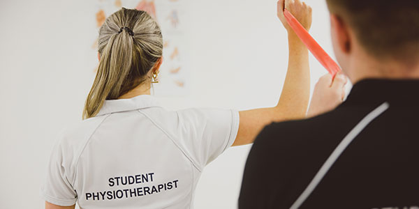 Two physiotherapy students use a resistance band