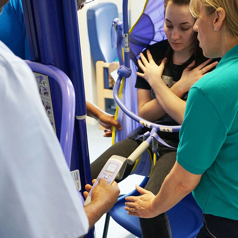 a woman being hoisted in a sling by health professionals