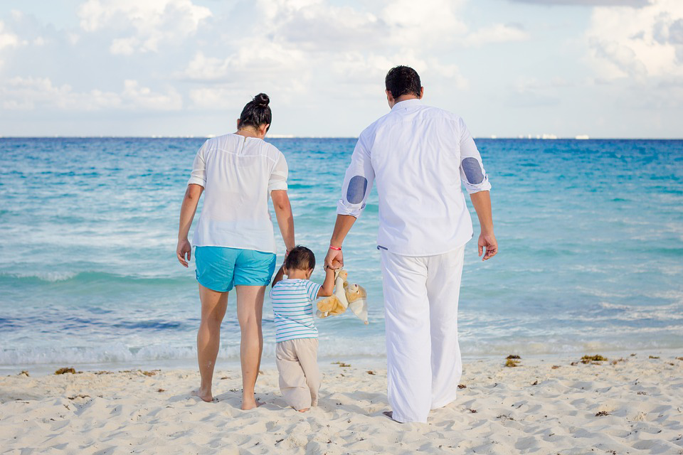 Mother and father walking with a toddler on a beach