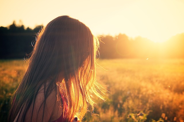 A picture of a young women enjoying the sunset in a rural setting.