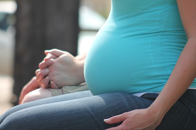 A picture showing a heavily pregnant women sitting in a waiting room.