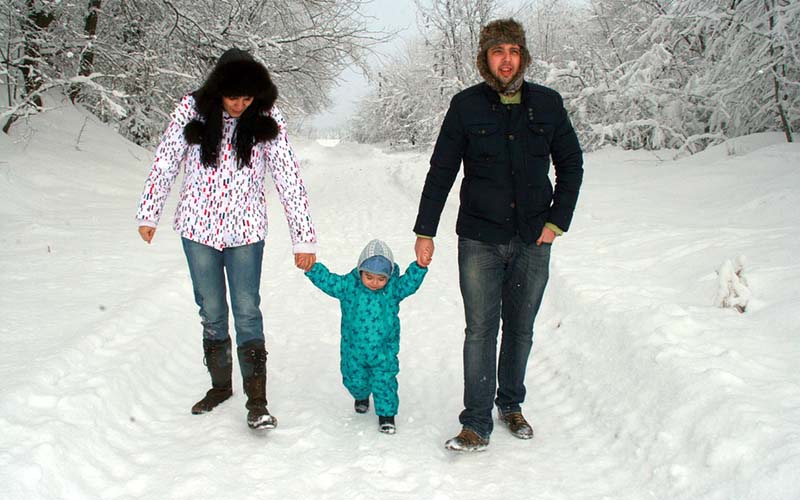 Two parents helping a child walk