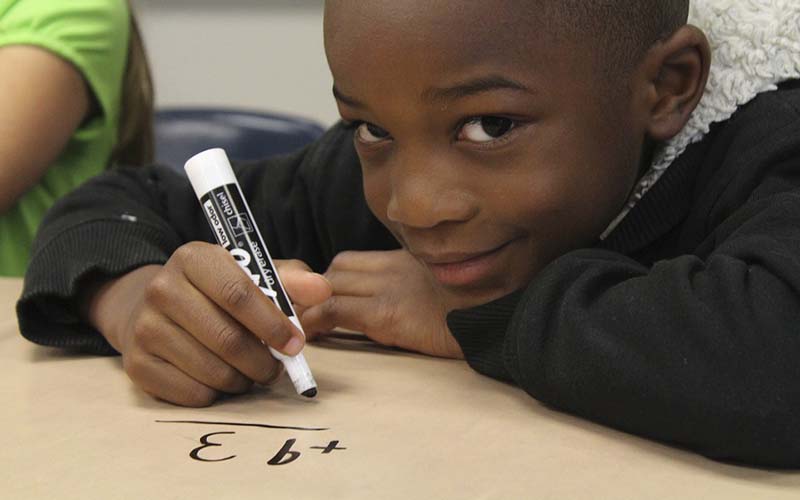 A boy doing maths on a table