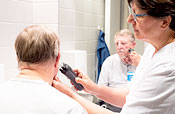 Nurse shaving male patient