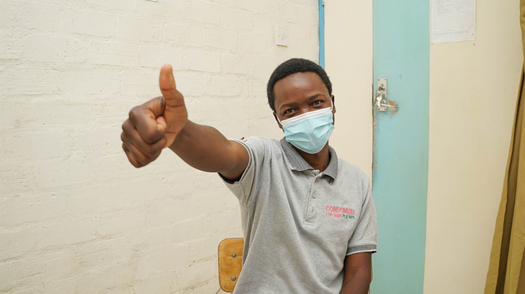 Male patient happy with thumbs up after vaccination.