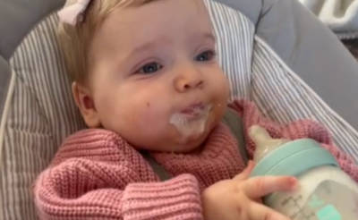 Baby spitting milk out of their mouth whilst holding bottle