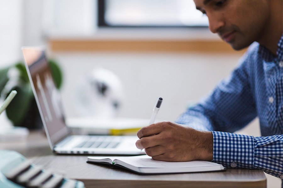 Researcher writing notes at his desk.