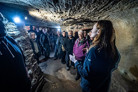 A tour guide talking to visitors in a sandstone cave.