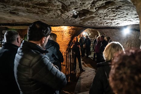 A tour guide showing visitors features of a sandstone cave.