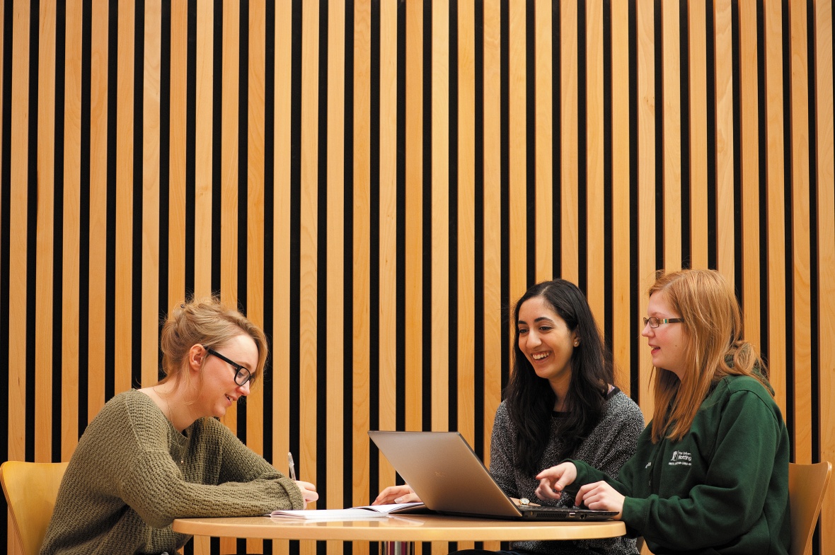 Three students working at a table in the Humanities building