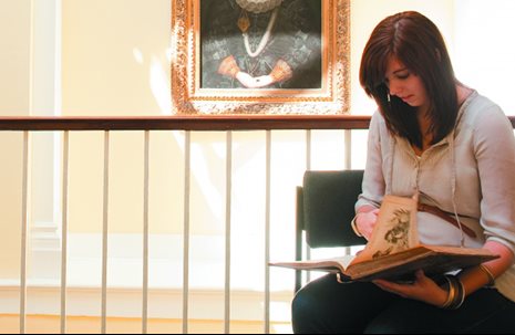 Undergraduate student reading near a historical painting