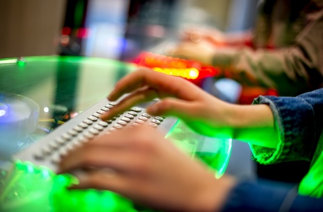 Hands hovering over a glowing computer keyboard
