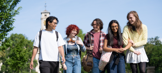 Mixed group of students walking through university grounds smiling and talking