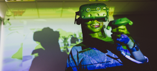 Student wearing VR headset and holding controller, laughing