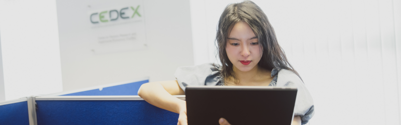 Student leaning on room divider looking at laptop