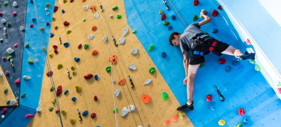 Student on climbing wall reaching for hold
