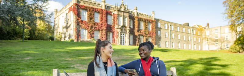 Two students sitting on bench outside Hugh Stewart Hall, University Park campus