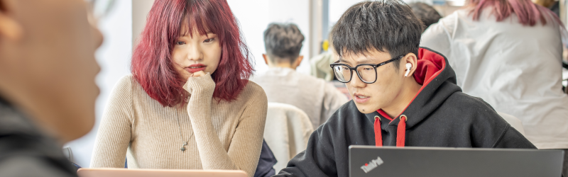 Two students concentrating on a laptop screen