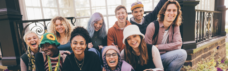 Mixed group of students crouching together laughing and smiling