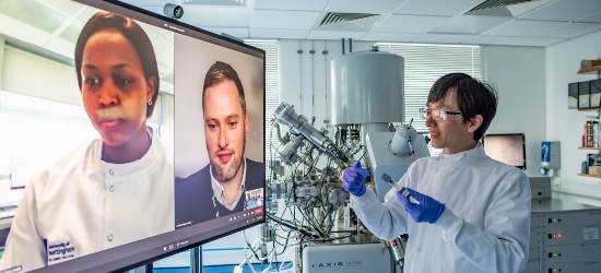 A scientist in a lab holding a video conference with two other researchers