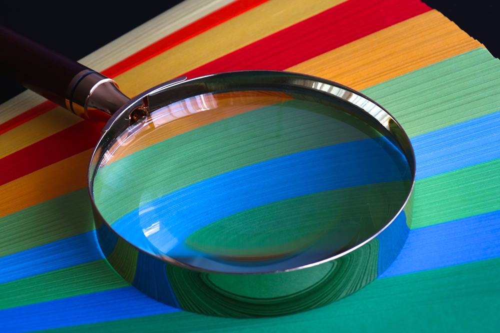 Close up of magnifying glass on coloured paper