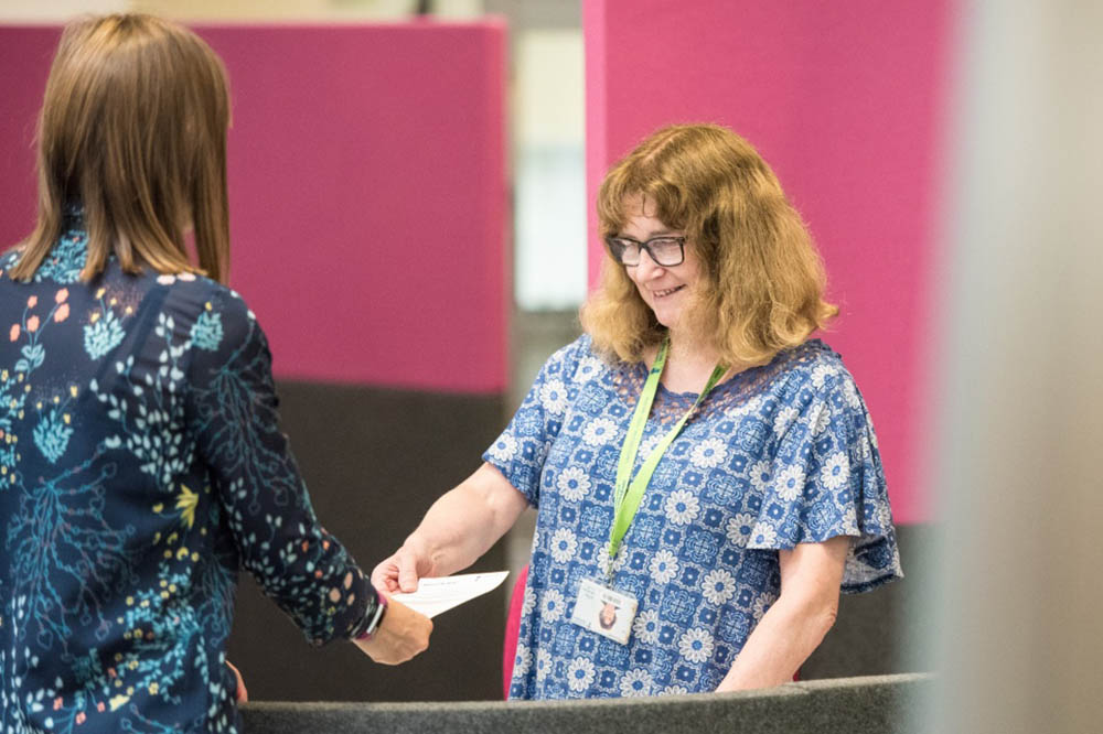 Image of a female member of staff helping a student in Hallward Library