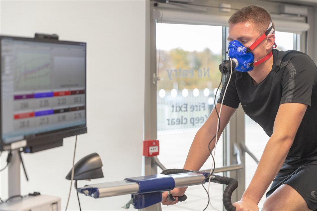 A student on an exercise bike, connected to a respirator