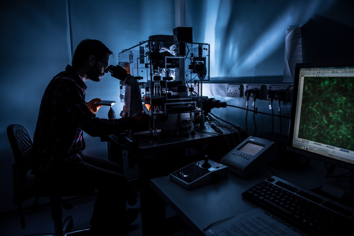 A student uses a microscope in a dark room