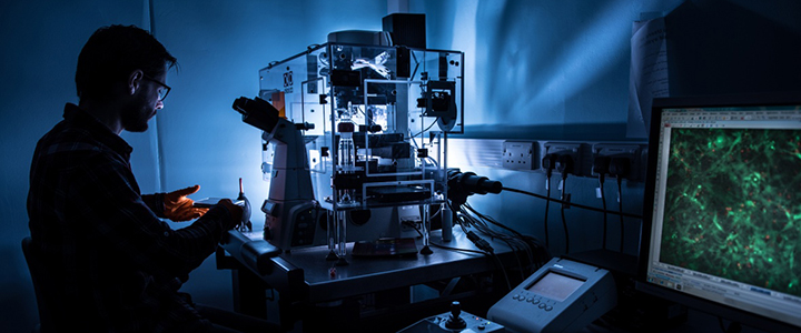 Male postgraduate student using a Deconvolution microscope in a Tissue Culture Laboratory