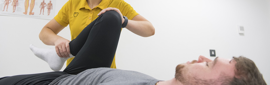A physio moving a sportsperson's leg in physiotherapy