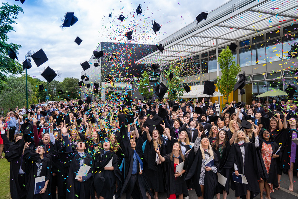 Graduates throwing their caps in the air while confetti rains down