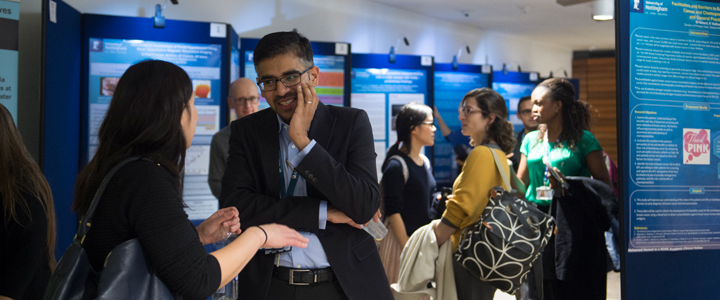 Academic Clinical Lecturer discussing a research poster in a crowded room