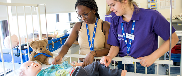 Two summer school students handling a child mannequin