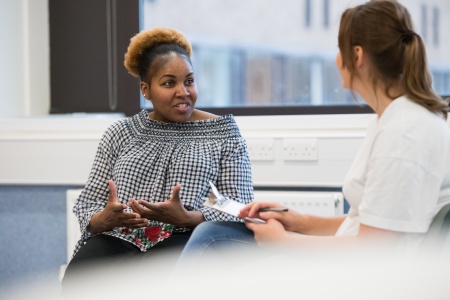 two women sat having a conversation in a hospital environment