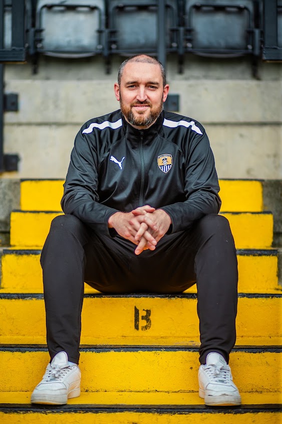 Dan Leivers sitting on steps at Meadow Lane wearing Notts County training gear