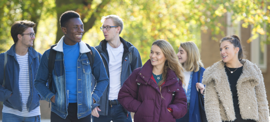 Mixed group of students walking outside under trees
