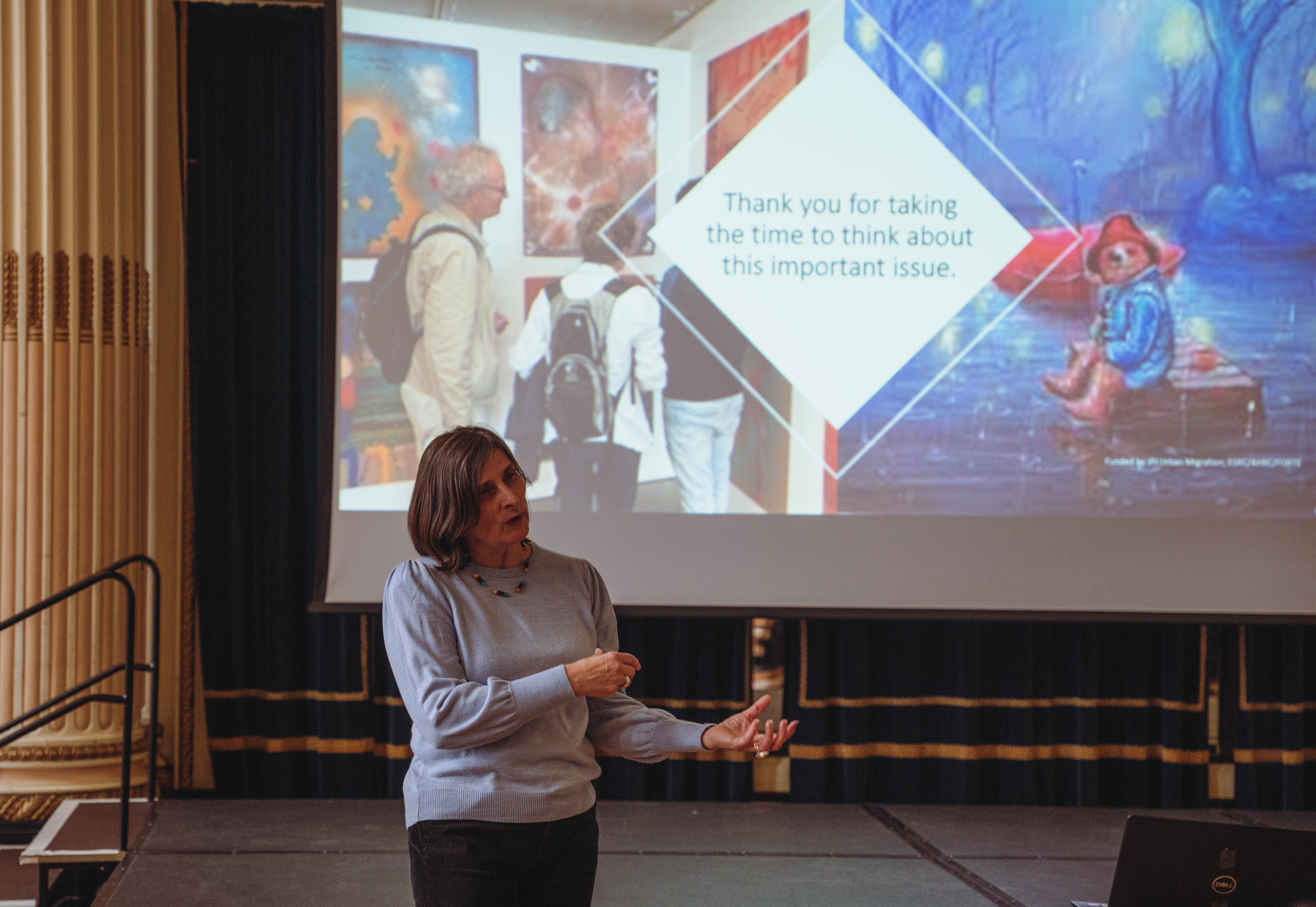 A white woman standing in front of a big screen