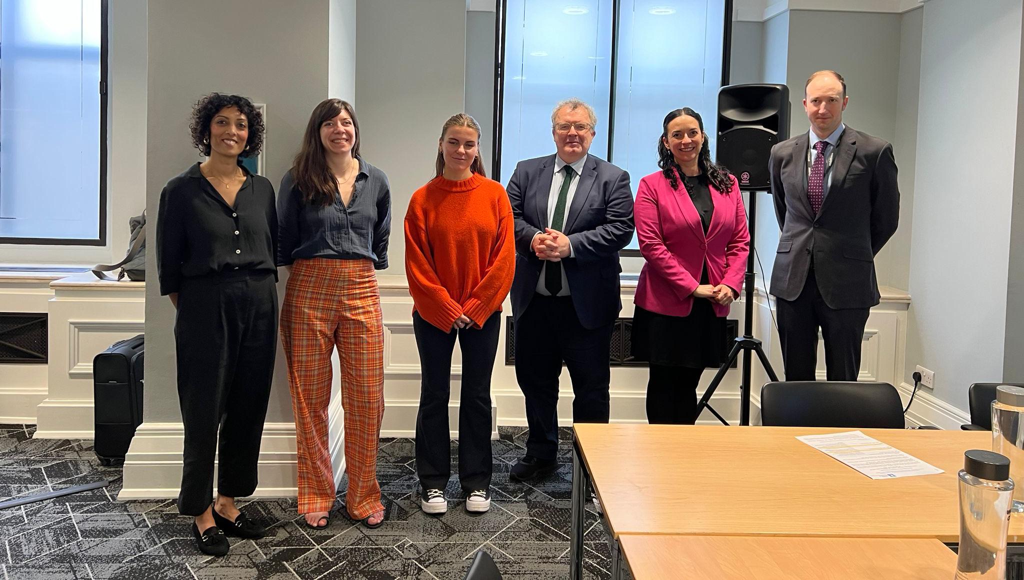 Image of 6 white male and female adults standing in a room