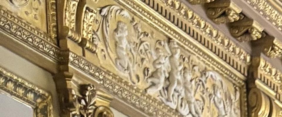 Two woman standing in a large room, smiling, wearing red jackets