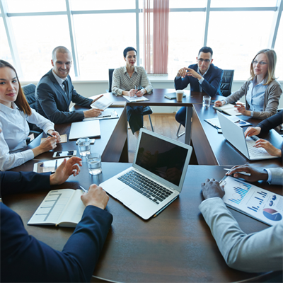 A group of people sitting in a board room, having a discussion